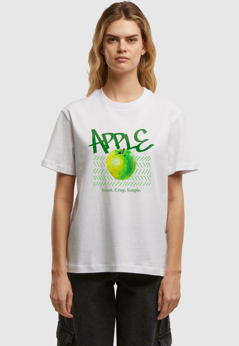 T-shirt en coton blanc avec un motif de pomme verte et le texte "APPLE" ainsi que les mots "Doux. Croustillant. Simple." en vert. Manches courtes, coupe décontractée.