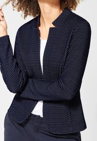 Námořnický texturovaný blejzr s geometrickým vzorem, uvolněný střih, otevřený přední díl a dlouhé rukávy. Obsahuje klopový límec a hladkou podšívku.