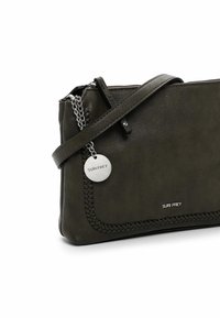 Borsa a mano in pelle verde scuro con bordo intrecciato, tracolla in catena argentata e una targhetta metallica rotonda. Presenta una chiusura con zip e una texture liscia.