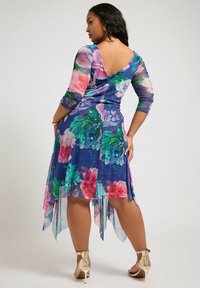 Kukallinen mekko läpikuultavasta kankaasta, jossa on tummansinisellä pohjalla suuria vaaleanpunaisia ja vihreitä kukkia, kolmanneksi hihat ja epäsymmetrinen helma.