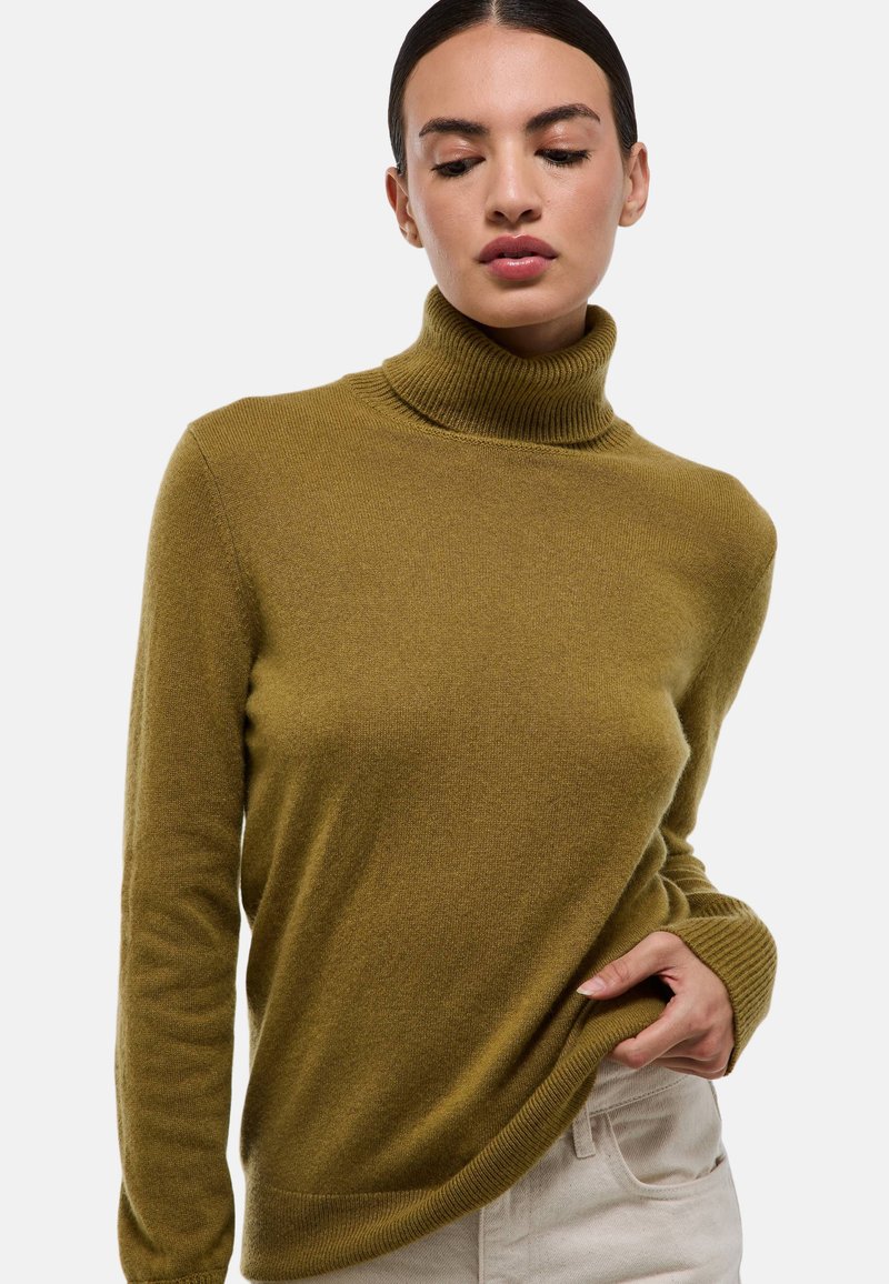 Pull col roulé vert olive en tissu doux avec des détails côtelés au col et aux poignets, présentant une coupe décontractée et des manches longues.