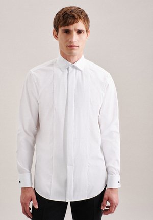 Chemise blanche avec un devant plissé, manches longues, col pointu et boutons de manchette noirs. Tissu lisse et rigide avec une coupe ajustée.