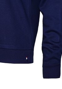 Navy sweatshirt featuring a ribbed cuff and hem, made from a soft fabric with a small tricolor logo near the bottom seam.