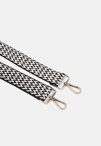 Gewebtes Stoffband im schwarz-weißen Zickzackmuster, mit Metallschnallen an jedem Ende zur Befestigung. Strukturiertes und langlebiges Design.