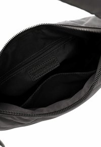Interno di una borsa nera con zip, realizzato in tessuto liscio. Presenta un'etichetta "EMILY & NOAH" e una piccola tasca con zip per l'organizzazione.