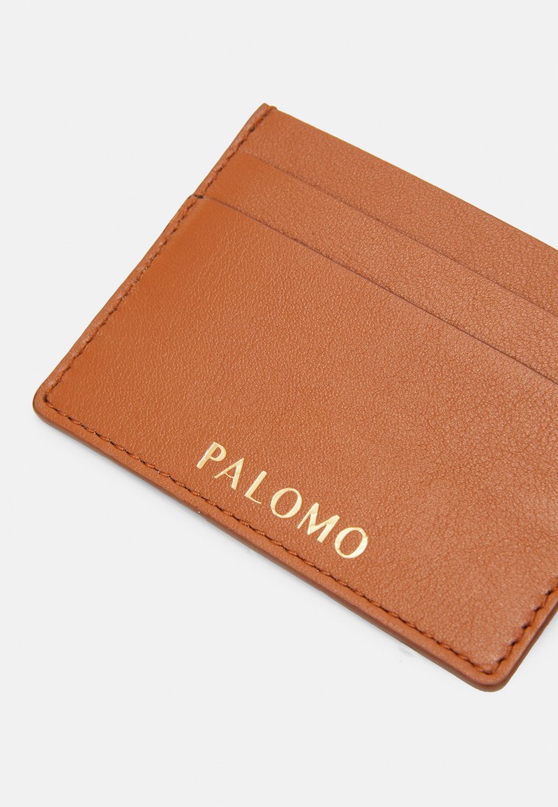 Brun læder kortholder med en tekstureret overflade, der har to lommer og præget "PALOMO" i guld på forsiden.