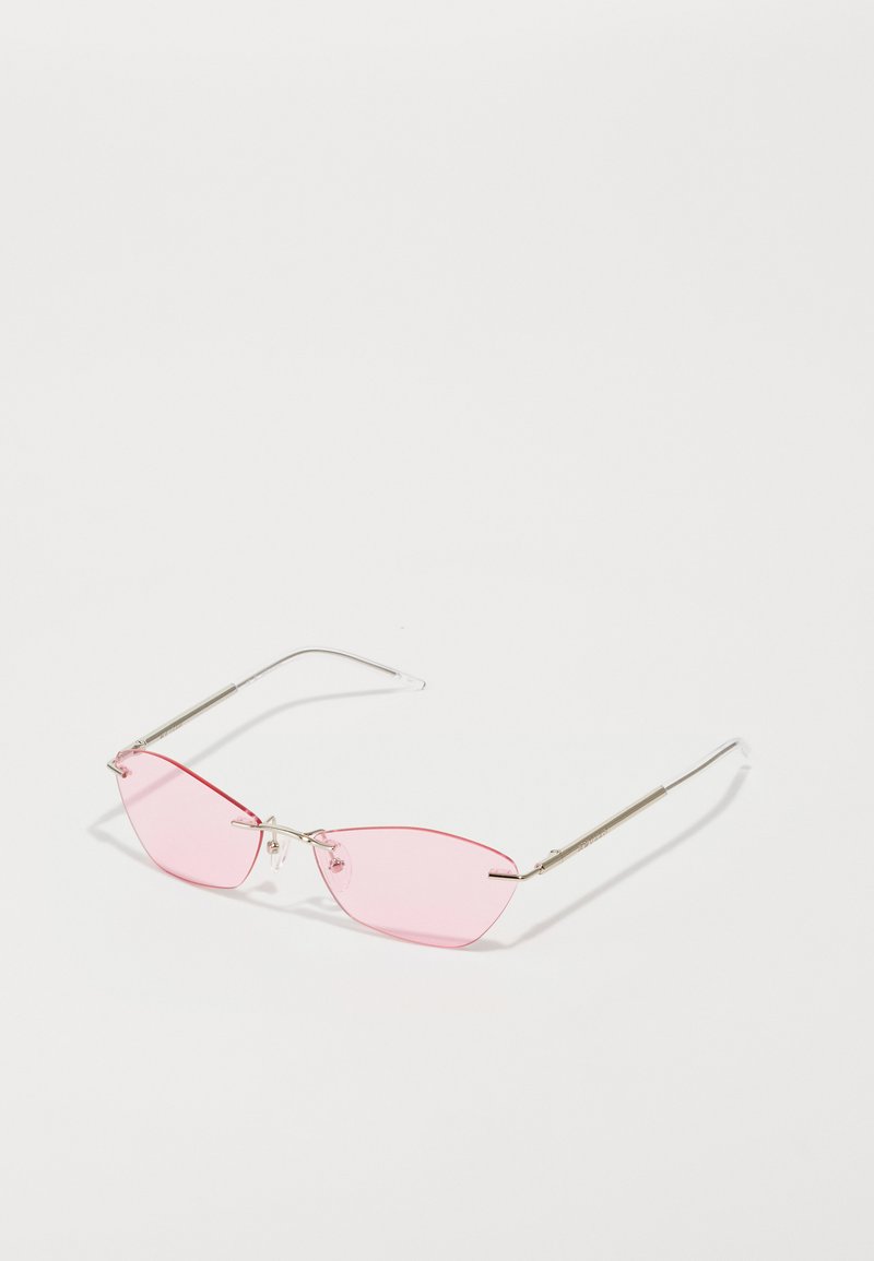 Svetle srebrne sunčane naočale s rimless roze obojenim staklima leže na beloj površini i bacaju blage senke.