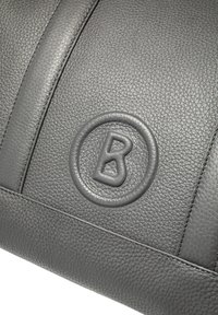 Borsa in pelle grigia con texture, caratterizzata da un logo circolare in rilievo con la lettera "B" ben visibile e dettagli cuciti a contrasto.