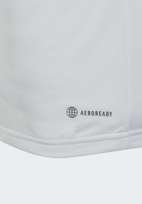 Camiseta deportiva blanca con una tela texturizada, que presenta el logotipo "AEROREADY" en negro cerca del dobladillo y un diseño elegante y minimalista.