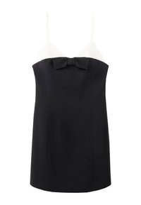 Camisole noir et blanc avec des bretelles fines, présentant un haut texturé blanc et un bas noir, souligné par un nœud au centre.