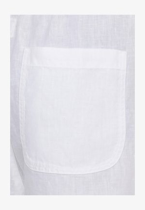 Tessuto di lino bianco con tasca quadrata cucita, fili visibili e trama naturale.