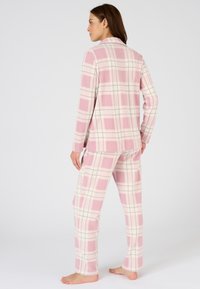 Conjunto de pijama a rayas en rosa en tejido suave, con mangas largas, una blusa con cuello y pantalones a juego con acentos en crema y azul.