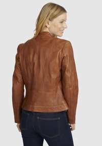 Bruine leren jack met een slank ontwerp, naadloze schouders en verticale stiksels. Gladde textuur met een licht glanzende afwerking.