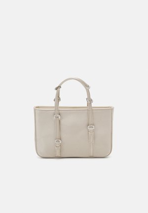 Sac à main beige au design structuré, avec deux anses courtes et des accents décoratifs en métal sur les sangles. Texture lisse et forme rectangulaire.