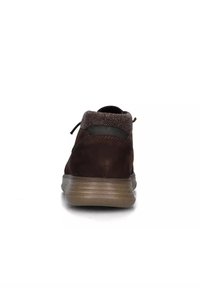 Scarpa in suede marrone con un colletto in tessuto testurizzato, una forma arrotondata e una suola in gomma marrone chiaro con scanalature orizzontali.