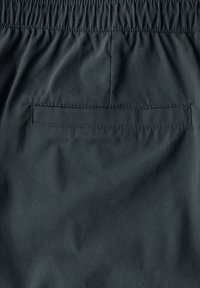 Shorts gris foncé en tissu léger, dotés d'une taille élastique et d'une poche arrière unique avec un rabat. Design minimaliste.