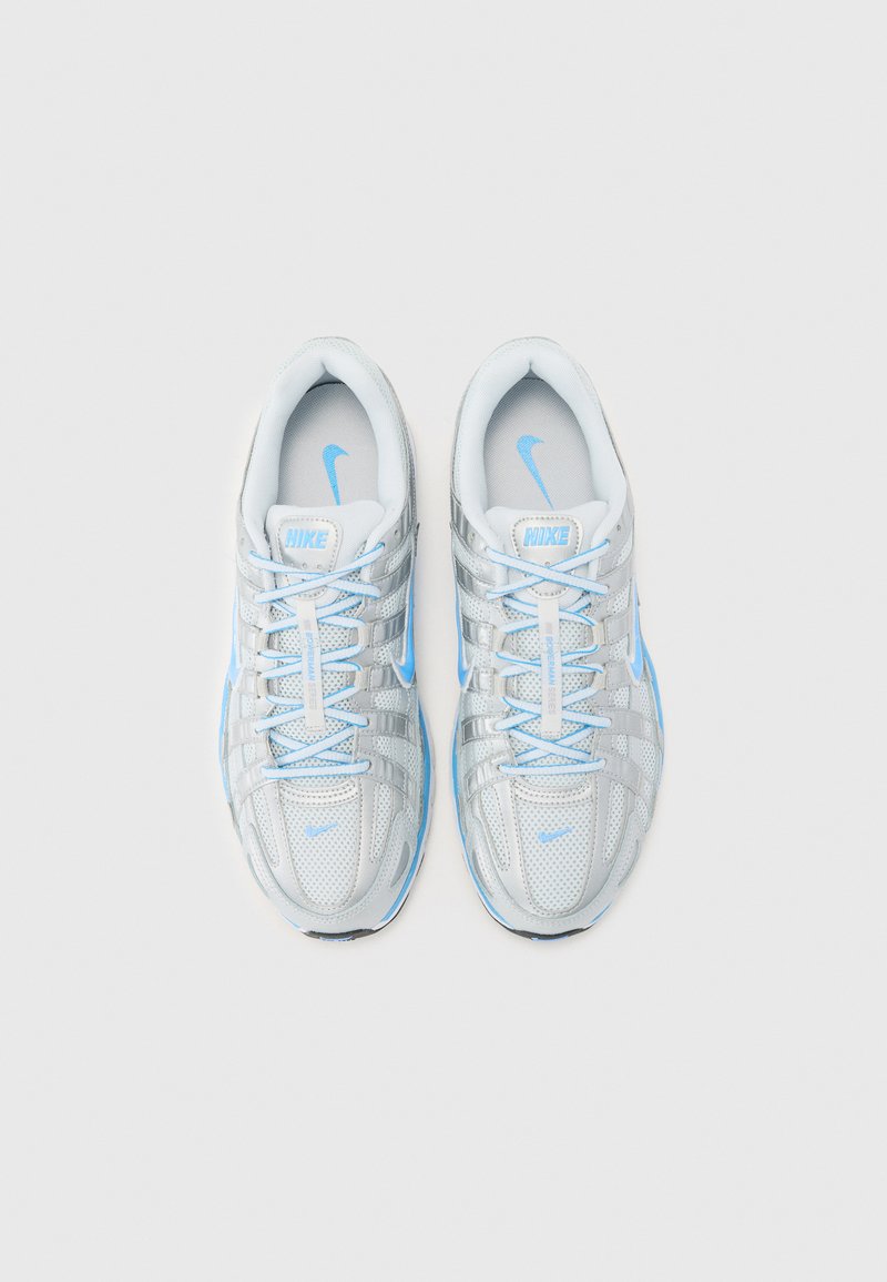Baskets Nike avec une tige en maille argent métallique, des accents bleu clair et des lacets blancs. Semelle rembourrée et texture respirante.