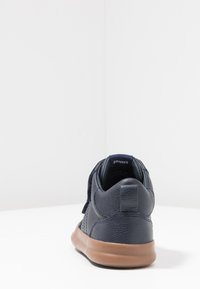 Sneaker in pelle blu navy con finitura testurizzata, dotato di suola in gomma e cinturino in velcro. Punta arrotondata e caviglia imbottita per comfort.