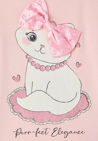 Ilustracja białego kota z różową satynową kokardą ozdobioną perłami, siedzącego na różowej błyszczącej macie, z sercowymi akcentami i napisem "Idealna elegancja."