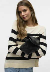 Maglione a righe in crema e nero, con maniche lunghe e una vestibilità rilassata, abbinato a una borsa in pelle nera, esposto con denim.
