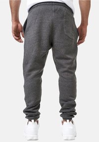 Gray sweatpants made of soft fabric, featuring a tapered fit, elastic waistband, and side pockets. Worn with white sneakers.