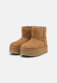 Bottines en suede marron à bout arrondi, doublure douillette et semelle épaisse et texturée. Agrémentées de coutures ton sur ton et d'un revers confortable.