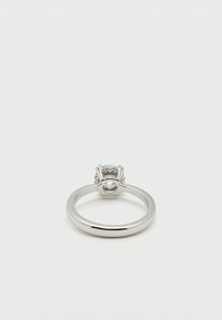 Ασημένιο δαχτυλίδι με ανυψωμένη βάση που κρατά στρογγυλό διαφανές πολύτιμο λίθο, φωτογραφημένο από το πλάι σε λευκό φόντο.