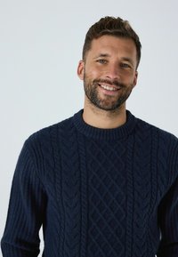 Marineblauer, kabelstrickpullover mit Rundhalsausschnitt und gerippten Bündchen. Die Strickstruktur und das Rautenmuster sorgen für visuelles Interesse.