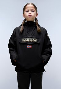 Svart pulloverjacka med hög krage, med en framficka, logotext, norsk flagga och en lös passform, tillsammans med mörka byxor.