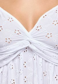 Rochie albă din bumbac cu decolteu adânc în V, bust răsucit și broderie florală, având decupaje deschise în întreaga țesătură.