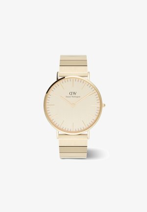 Montre dorée avec un cadran rond minimaliste, un visage beige clair et un bracelet métallique fin avec des maillons horizontaux. Des repères indiquent les heures.