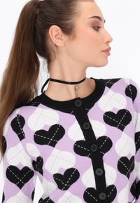 Cardigan a maglia con sfondo lilla e motivi a cuore neri e bianchi. Bottoni neri e un colletto nero a contrasto. Tessuto testurizzato.