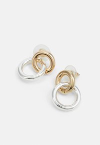 Gold and silver-tone metal earrings featuring interlocking circular designs with smooth finishes and transparent backs for secure wear.