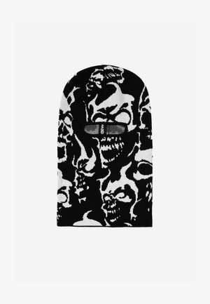 Crna i bijela pletena balaklava s uzorkom lubanja, s otvorima za oči i oznakom sprijeda. Mekana tekstura.