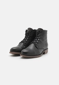 Botas de cuero negro hasta el tobillo con punta redondeada, cordones en la parte delantera y cremallera lateral. Presentan un tacón de madera marrón en capas y una textura suave.