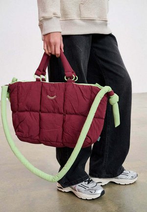 Kurtkowana bordowa torebka z zielonymi akcentami, z wyściełanym zewnętrzem, dwoma uchwytami oraz odpinanym paskiem na ramię. Charakterystyczny motyw uśmiechu.