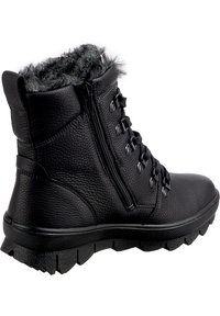 Botas negras hasta el tobillo hechas de cuero texturizado, con un cuello de pelo sintético, cierre de cremallera y suela de goma robusta con un dibujo pronunciado.