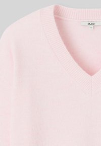 Pull léger rose en V avec un col côtelé, fabriqué en matériau doux. Présente un design simple sans motifs ni accessoires supplémentaires.
