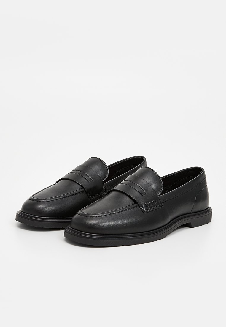 Schwarze Lederloafers mit glatter Textur, die über eine gestickte Verzierung im oberen Bereich und eine abgerundete Zehenpartie verfügen, auf einer flachen Gummisohle.