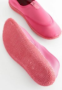 Rosa Slipper aus glattem Stoff-Obermaterial und strukturiertem Gummisohle mit kleinen Vorsprüngen für Traktion und Grip.