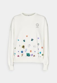 Sweat-shirt blanc à manches longues avec de petits motifs floraux multicolores dispersés près de l'ourlet et un logo circulaire avec « Liberty » sur la poitrine.