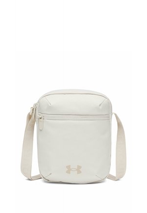 Kleine beige crossbodytas met voorvak met rits, verstelbare band en Under Armour-logo aan de onderkant middenvoor.
