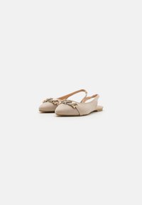 Zapatos de ante beige tipo slingback con punta redondeada, que presentan un detalle trenzado en tono dorado en la parte delantera y un tacón bajo y plano.