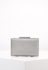Rektangulær sølv clutch taske med struktureret overflade, vist på en hvid hjørnepiedestal imod en ensfarvet hvid baggrund.