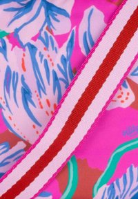 Bloemenstof in roze, blauw en groen met een gestructureerd oppervlak, overtrokken met een rood-witte gestreepte lintaccent.
