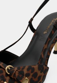 Sandale à talons hauts en imprimé léopard avec un design marron et noir, comportant un accent doré et des brides fines. Texture lisse et bout pointu.