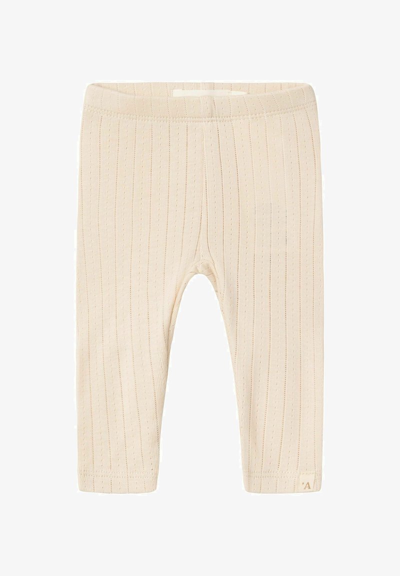 Bež riblih tajica izrađenih od mekog materijala, s laganom teksturom, elastičnim pojasom i malom oznakom na rubu.