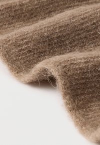 Brunt tekstureret stof med en blød, fnugget overflade, der viser et vævet mønster og en blid fald.