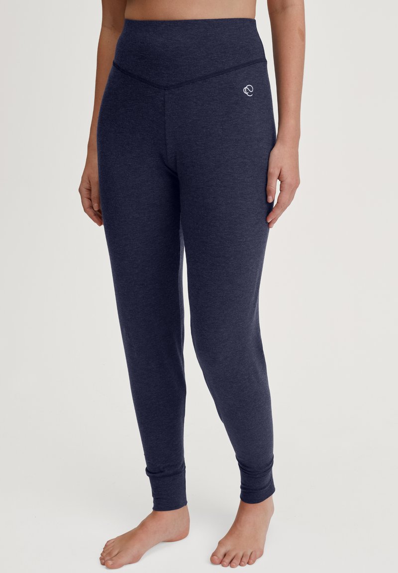 Marineblauwe activewear broek in zachte, gestructureerde stof met een hoge tailleband, taps toelopende benen en een klein logo op de linker heup.