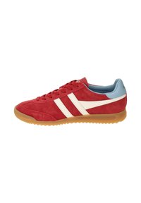Zapatilla de ante roja con rayas blancas, acentos azules en el talón y suela de goma. Presenta un perfil bajo y diseño de cordones.